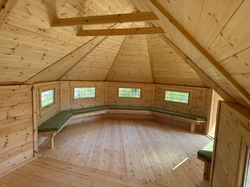 Log cabin with benches around the edge with green cushions, 17m 3m extension and porch