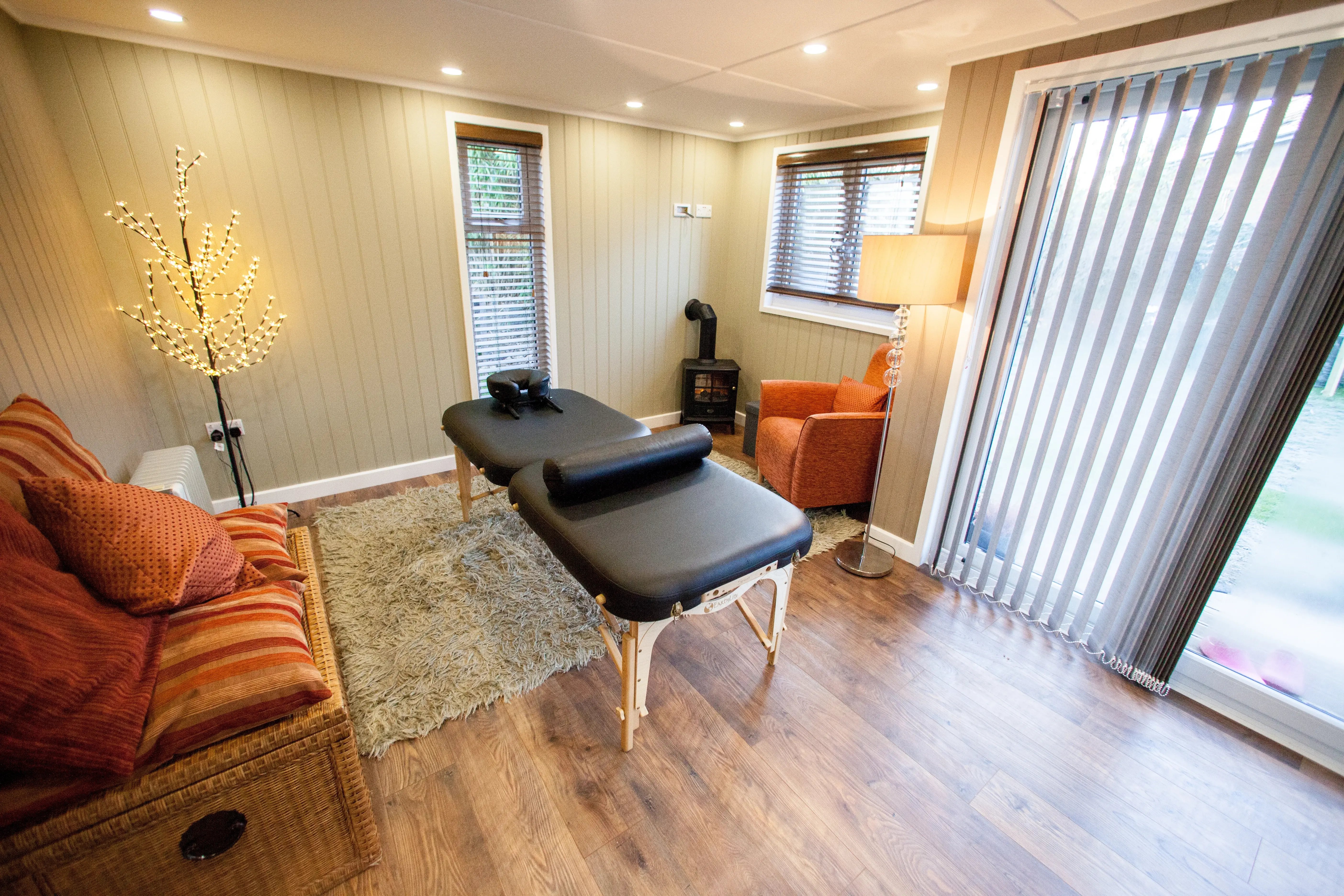 A warmly light and decorated modern treatment room with a massage table in the centre of the cabin.