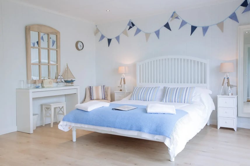 A modern glamping lodge with a king sized bed, bedside tables and a side table. The room is decorated with nautical themed decorations.
